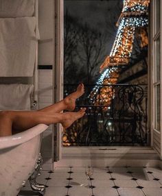 a woman is sitting in a bathtub with the eiffel tower behind her