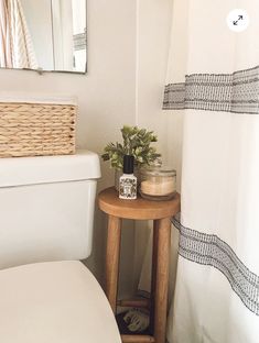 a white toilet sitting next to a wooden table with a plant on top of it