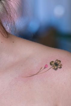 a woman with a flower tattoo on her shoulder and behind her neck is a four leaf clover