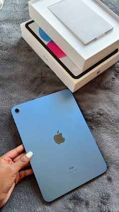 a person holding an apple ipad in their hand next to the box that is open