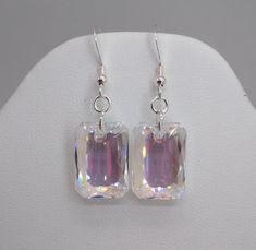 These beautiful sterling silver earrings have sparkling Swarovski Crystal Clear Shimmer Emerald Cut-shaped drops hung on a closure of your choice.Pendant Size:  16mm Approx Length of Whole Earring: 1 3/4 - 2"Choose Closure: Fishhook Earwire or LeverbackEarwires come with rubber earnut backs in order to secure them on your ears; leverback have a secure attachment.**Packaged in a cotton filled gift box**Matching Necklace Availablehttps://www.etsy.com/SunshineJazzyJewels/listing/866118228/sterling- Rectangular Crystal Earrings For Gifts, Emerald Cut Earrings, Rectangle Pendant, Cut Earrings, Secure Attachment, Heart Drop Earrings, Matching Necklaces, Emerald Cut, Crystal Clear