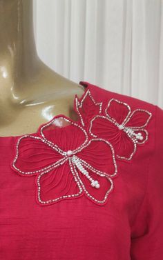 a mannequin head wearing a red dress with flowers on the chest and shoulder