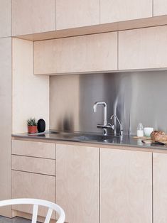 a modern kitchen with stainless steel appliances and wood cabinetry, along with a white chair