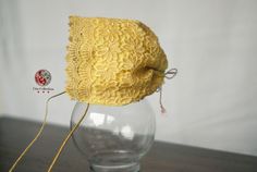 a yellow hat sitting on top of a glass vase filled with water and twine