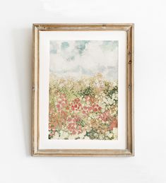 a painting hanging on the wall above a vase with flowers in it and an empty wooden frame