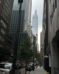 a city street with tall buildings and cars parked on the side of the road in front of them