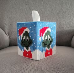 an image of a christmas themed tissue box on the couch with santa hats and snowflakes