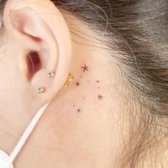 a woman's behind the ear with small stars on her left side