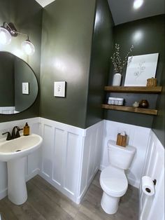 a white toilet sitting next to a sink in a bathroom under a large round mirror