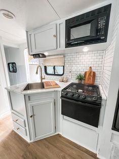 a kitchen area with stove, microwave and sink in a recreational vehicle or camper