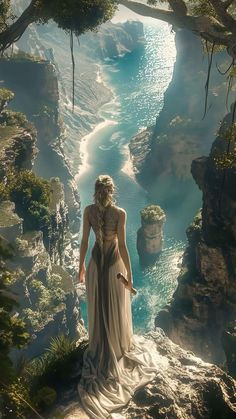 a woman standing on top of a cliff next to a river