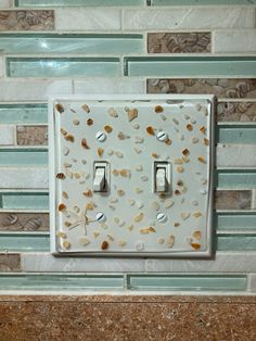 a white light switch sitting on top of a wall next to a tile backsplash