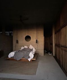 a bed sitting in the middle of a room next to a wall with wooden slats