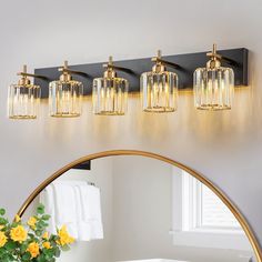 a bathroom light fixture with four lights on the wall above it and a mirror in front of it