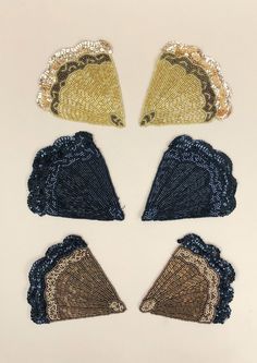 four pieces of blue and gold sequins with fan shaped doily on them