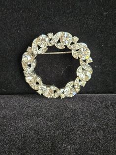 This circle brooch has entwining rows of small rhinestones around large rhinestones that catch all the lights to reflect beauty. There is a signature on the back but I couldn't make it out. Please look at the pictures carefully as this is the item you're purchasing.  I do combine shipping on multiple items. Elegant Round Brooches With Rhinestones, Elegant Round Rhinestone Brooches, Round Rhinestone Brooches For Formal Occasions, Round Formal Brooches With Rhinestones, Formal Round Brooches With Rhinestones, Formal Round Rhinestone Brooches, Crystal Round Brooch For Party, Round Crystal Brooch For Party, Anniversary Rhinestone Round Brooches