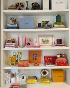 a white book shelf filled with lots of books and other assorted items on top of it