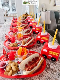 a long table filled with hot dogs and other foods on red trays next to each other