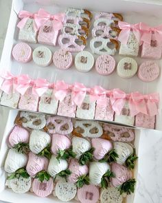 two boxes filled with different types of donuts in pink and white ribbons on top of each box