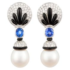 The blue sapphire, diamond and pearl earrings feature a round design set with diamonds set en pave on the ear around a symmetrical spray of black onyx. The tops suspend 2 oval cut faceted Ceylon sapphires of brilliant color for a total weight of 4.43 carats. The design is complete with two large and lustrous South Sea pearls measuring 17 x 16mm. The total weight of round diamonds is 5.85 carats. All of our pearls are untreated: their natural color and high luster have not been enhanced in any wa Pearl Earrings Designs, Diamond Tops, Pink Sapphire Earrings, Vintage Drop Earrings, Sapphire And Diamond Earrings, Blue Sapphire Necklace, Pearl And Diamond Earrings, Blue Sapphire Diamond, Sea Pearl