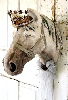 a white horse with a crown on it's head hanging from the side of a door