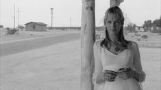 a woman standing next to a pole holding a cup