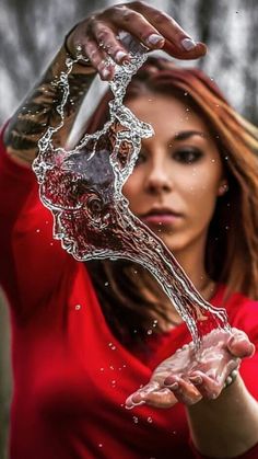 a woman in red shirt holding water from a faucet with her hands over her head