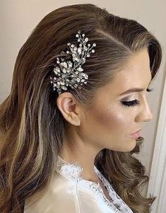 a woman with long hair wearing a white dress and a crystal headpiece in her hair