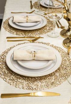 a table set with white and gold place settings