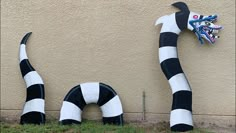 two large black and white striped sculptures next to a wall with a dragon on it