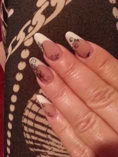 a woman's hand with white and black nail designs on it, holding onto her nails