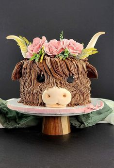 a cake shaped like a cow with flowers on its head