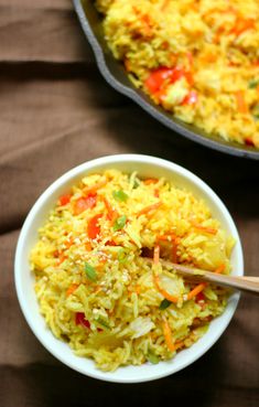 two bowls filled with rice and vegetables on top of a brown cloth covered tablecloth