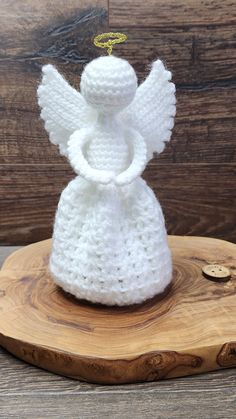 a white crocheted angel sitting on top of a wooden board