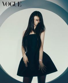 a woman with long hair standing in front of a white wall wearing a black dress