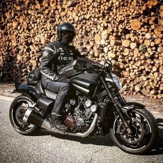 a man sitting on top of a motorcycle next to a pile of logs