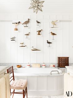 a bathtub with birds on the wall above it and two chairs next to it