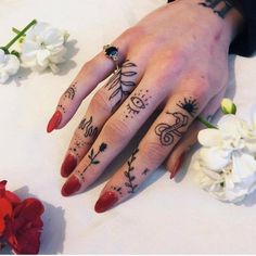 a woman's hand with tattoos on it and flowers in the background next to her