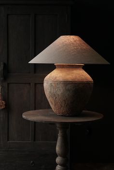 a lamp sitting on top of a table next to a wooden door with a light on it