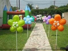 several balloons are placed on sticks in the grass next to a brick path that leads to a playground