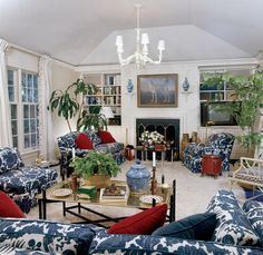 a living room filled with blue and white furniture next to a fire place covered in plants