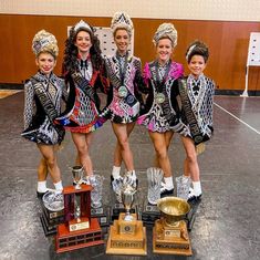 four girls in costumes standing on top of trophies and posing for the camera with their arms around each other