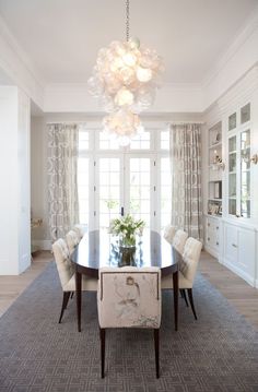 a dining room table with chairs and a chandelier hanging from it's ceiling