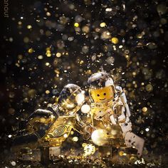 a lego man sitting on top of a yellow motorcycle in the rain with gold flakes all around him