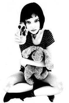 a woman sitting on the floor holding a teddy bear and pointing at something in her hand