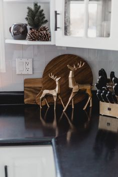 two wooden reindeer figurines sitting on top of a counter next to a knife holder