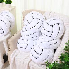 two white pillows with black lines on them sitting on a chair next to a potted plant