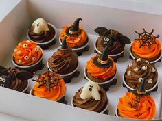 cupcakes decorated with chocolate frosting and spooky decorations in a box