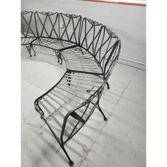 a curved metal bench sitting on top of a cement floor