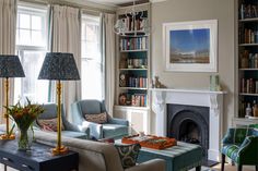 a living room filled with furniture and a fire place in front of a window covered in bookshelves